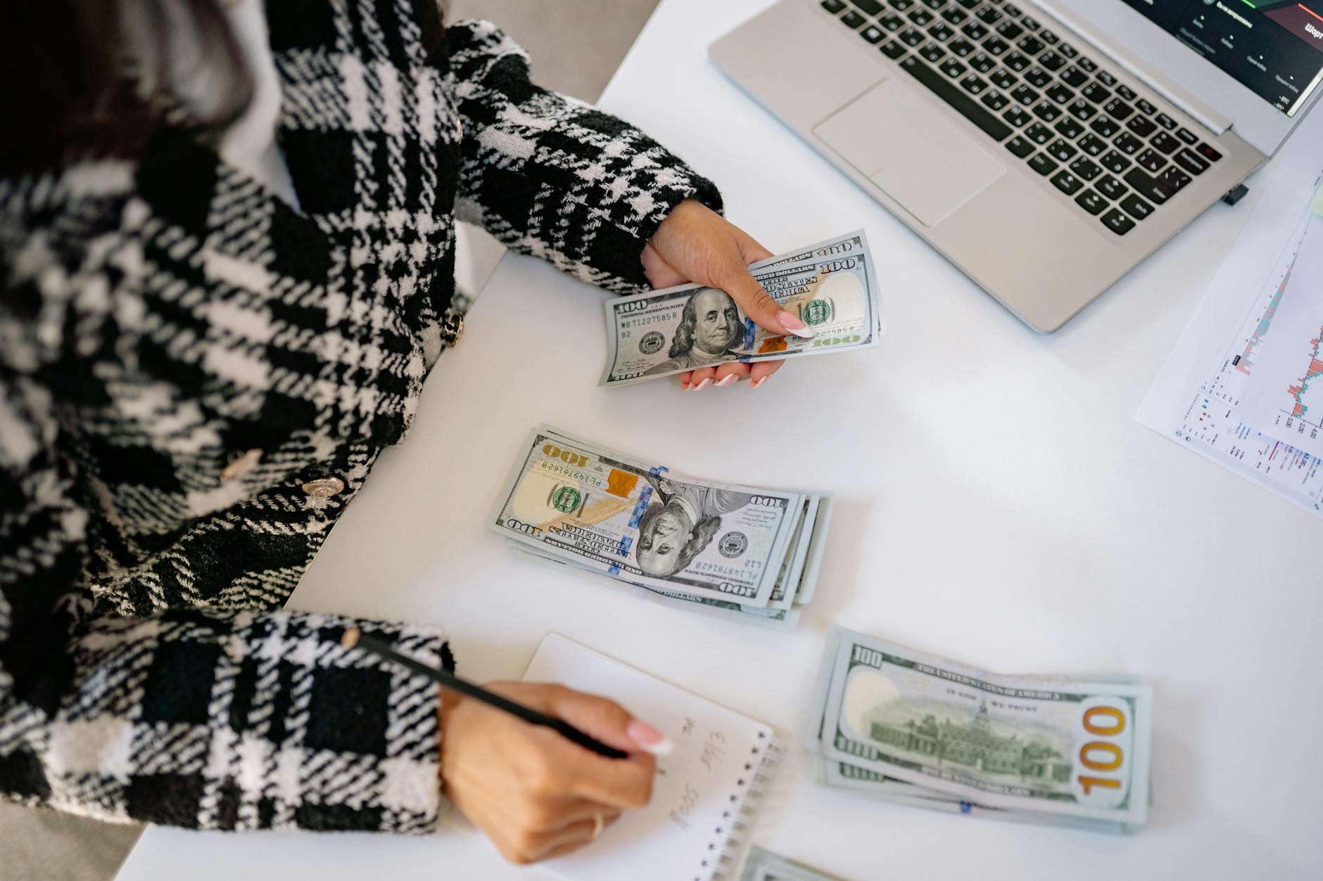 hand of a woman holding cash and a pencil